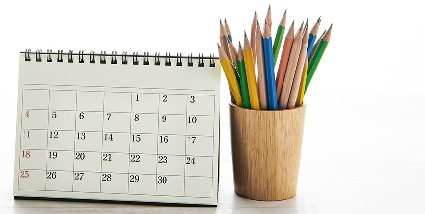 A calendar and a pot of pencils